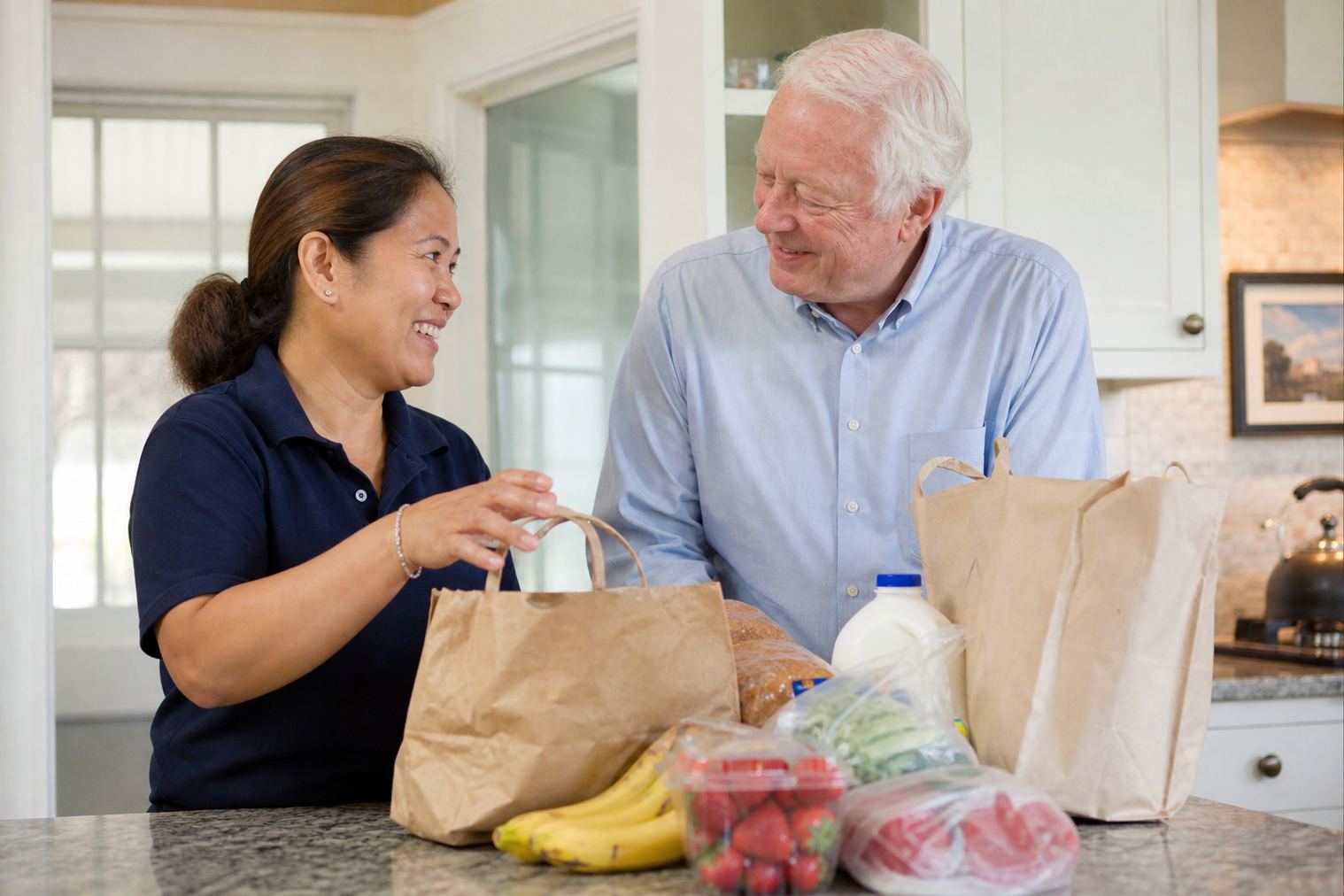 A caregiver unpacking groceries with an older adult at home in Lombard